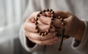 Hands holding a wooden rosary with crucifix