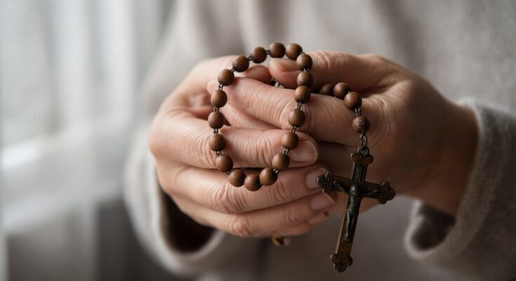 Hands holding a wooden rosary with crucifix
